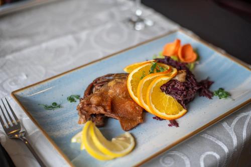 a plate of food with a piece of meat and orange slices at Hotel Marea Neagra in Sinaia