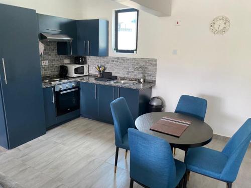 eine Küche mit blauen Schränken sowie einem Tisch und Stühlen in der Unterkunft Ibex Blue 2 Bedroom in Lusaka