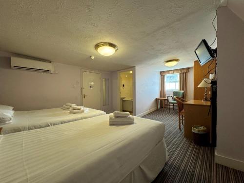 Habitación de hotel con 2 camas y escritorio en The Chatsworth Hotel en Worthing