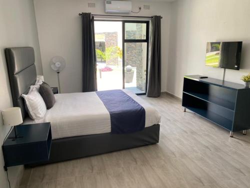 ein Schlafzimmer mit einem Bett, einer Kommode und einem TV in der Unterkunft Ibex Blue 2 Bedroom in Lusaka