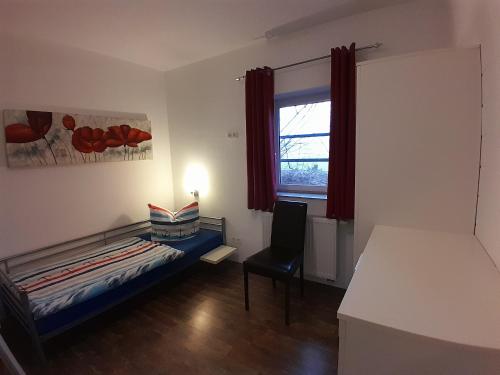 1 dormitorio con 1 cama, 1 silla y 1 ventana en Wikingerland Typ 1 Erdgeschoss, en Langballig