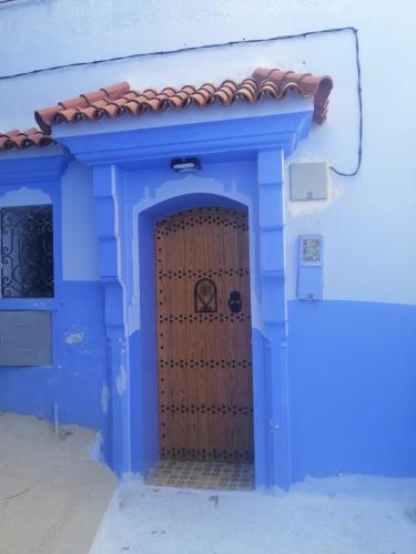 uma casa azul com uma porta azul com um telhado vermelho em Dar issam em Chefchaouen