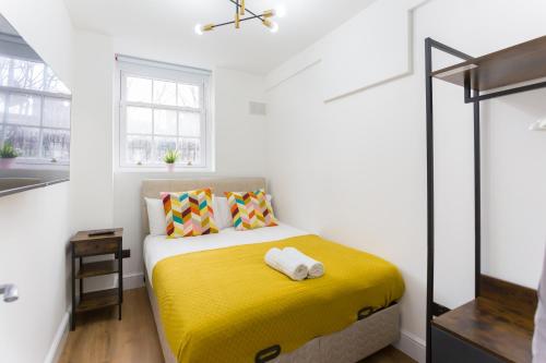 - une chambre avec un lit et une couverture jaune dans l'établissement City Centre One Bedroom Apartment Next to Station, Newly Renovated, à Londres