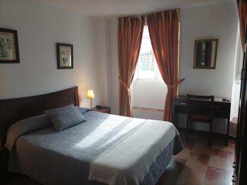 a bedroom with a bed and a desk and a window at Hostal San Cayetano in Ronda