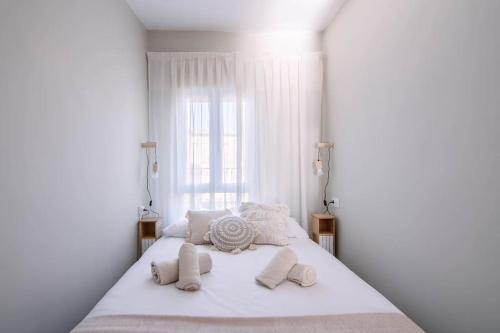 a white bed with white pillows and a window at El Rincón de Baco in Alesanco