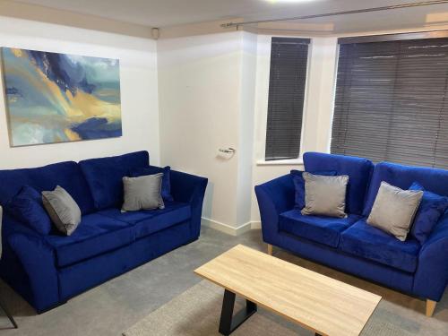 a living room with a blue couch and a table at Convenient 2 Bedroom Ground floor Apartment with Parking in Leeds in Pudsey