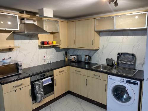 a kitchen with a sink and a washing machine at Convenient 2 Bedroom Ground floor Apartment with Parking in Leeds in Pudsey