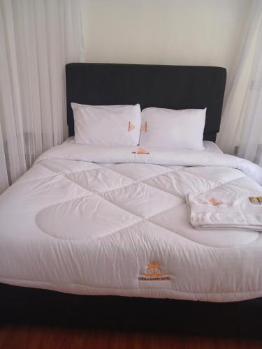 Cama blanca con sábanas y almohadas blancas en TAWALA GARDEN HOTEL en Nairobi