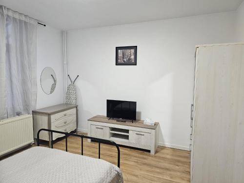 um quarto branco com uma cama e uma televisão em Renovated private room em Bruxelas
