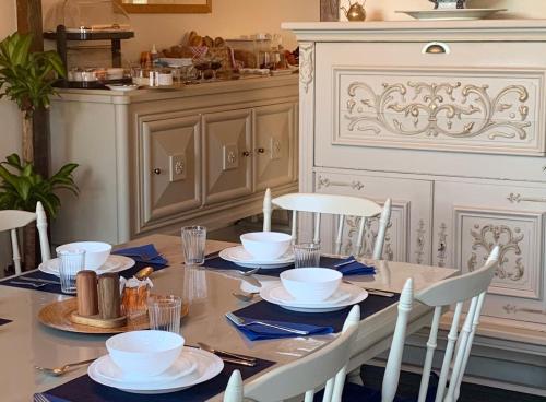- une table à manger avec des serviettes bleues et des plats blancs dans l'établissement Chateau de Chambres Mont St Michel, à Saint-James