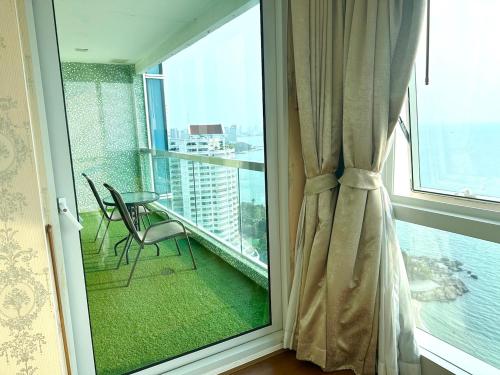 a balcony with a table and chairs and a window at Oceanfront Luxury Condo in Pattaya with Private Beach and Inifinity Pool - NOT A HOTEL 30 Day Stay Minimum in Pattaya North
