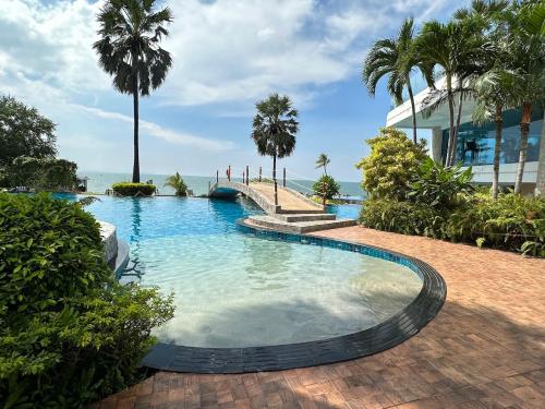 a swimming pool with palm trees and a building at Oceanfront Luxury Condo in Pattaya with Private Beach and Inifinity Pool - NOT A HOTEL 30 Day Stay Minimum in Pattaya North