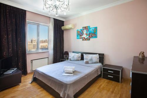 a bedroom with a bed with a chandelier and a window at Leyla Apartments 1 in Baku