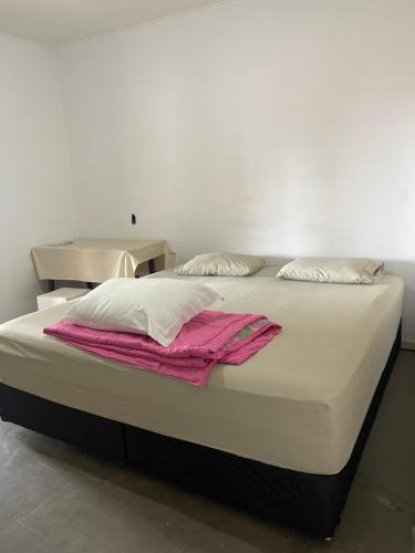 uma cama grande com lençóis brancos e almofadas em Estações em Campinas