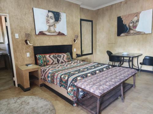 a bedroom with a bed with a table and portraits on the wall at South Gate Country Lodge in Polokwane