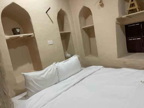 The traditional house في نزوى‎: سرير في غرفة مع ساعة على الحائط