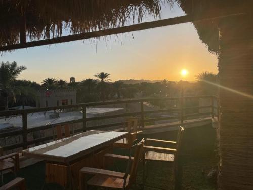 a sunset over a deck with a table and chairs at The traditional house in Nizwa
