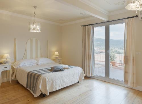 a white bedroom with a bed and a large window at Palazzo Pischedda in Bosa