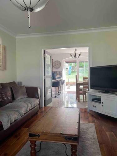 a living room with a couch and a flat screen tv at Spacious 4 bedroom house with large garden in Belfast