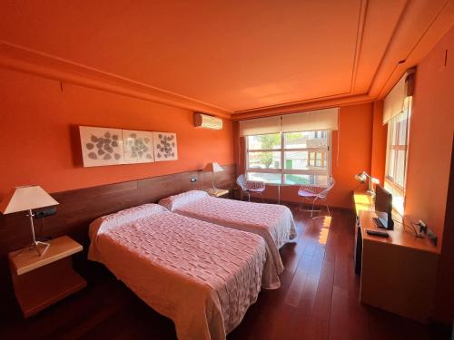2 łóżka w pokoju z pomarańczowymi ścianami w obiekcie PENSIÓN EL CARRO w mieście Utiel