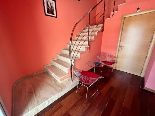 ウティエルにあるPENSIÓN EL CARROの赤い壁の階段、椅子2脚、テーブル