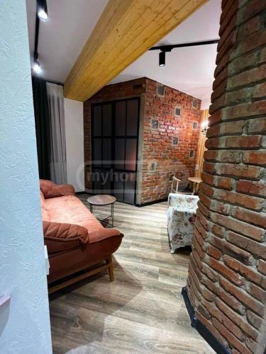 ein Wohnzimmer mit einer Backsteinwand und einer Couch in der Unterkunft Apartment in Tbilisi Dadiani 3 in Tbilisi City