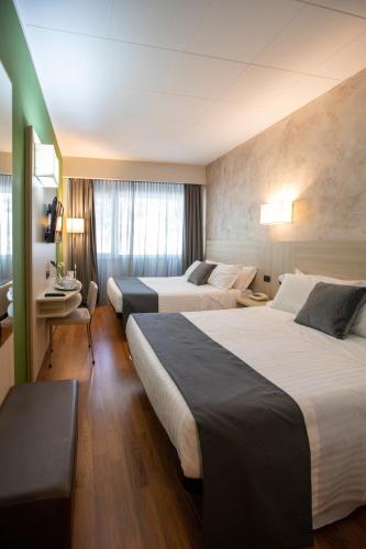 a hotel room with two beds and a desk at Hotel Palace del Conero in Osimo
