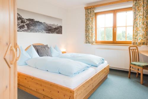 Schlafzimmer mit einem Holzbett mit weißer Bettwäsche in der Unterkunft Hotel Pension Appartement Kristall in Tröpolach