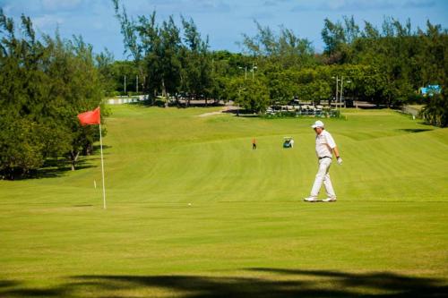 Ein Mann, der mit einer roten Flagge auf einem Golfplatz läuft. in der Unterkunft Sea-Renity Hideaway (Studio Apt) in Woods