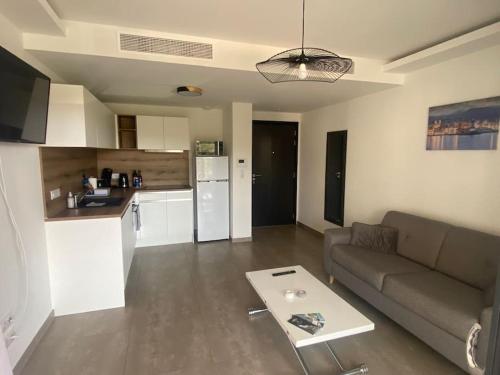 un salon avec un canapé et une table et une cuisine dans l'établissement Ajaccio : superbe appartement dans résidence neuve, à Ajaccio
