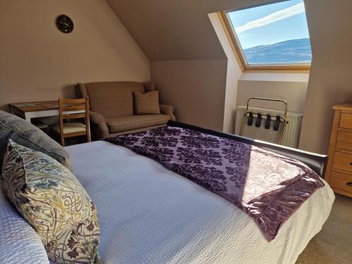 a bedroom with a bed and a window and a chair at Croft 17 in Ullapool