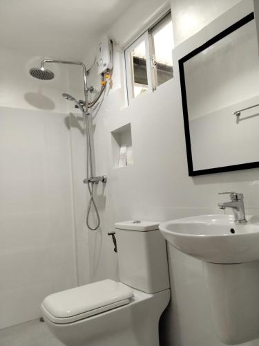 a white bathroom with a toilet and a sink at Moalboal Beach Front Hotel in Moalboal