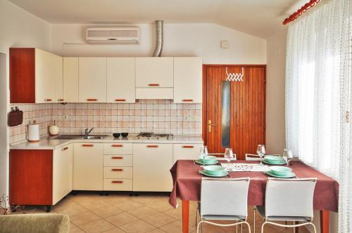 a kitchen with a table and chairs and a kitchen with white cabinets at Apartment Anita in Pula