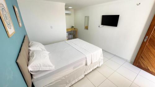 卡斯卡韋爾的住宿－Pousada Maré Forte，卧室配有白色的床和电视。
