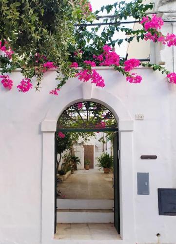 une arche avec des fleurs roses sur un bâtiment blanc dans l'établissement Casa Coltura, à Parabita