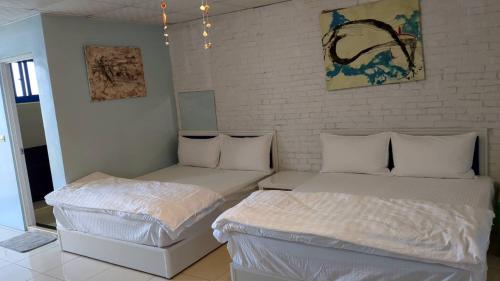 2 Betten in einem Zimmer mit weißen Wänden in der Unterkunft 布袋愛琴海Aegean Sea B&B Budai in Budai