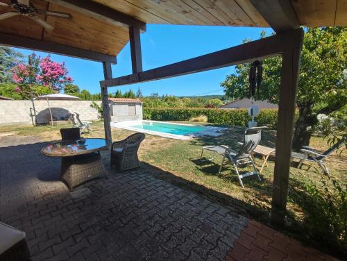 a patio with a table and chairs and a swimming pool at Chambre au coeur du Luberon in Céreste