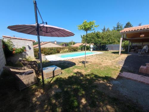 a patio with an umbrella and chairs next to a pool at Chambre au coeur du Luberon in Céreste