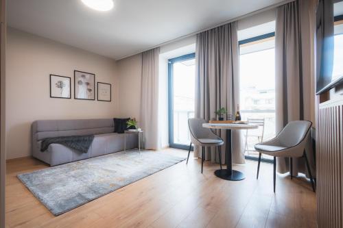 GRAY APARTMENT في بانسكا بيستريتسا: غرفة معيشة مع أريكة وطاولة مع كراسي