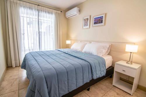 a bedroom with a bed with a blue blanket and a window at Apartment 1720 in Mendoza