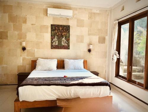 a bedroom with a bed with a painting on the wall at Suastika Guest House in Ubud