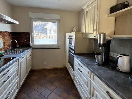 uma cozinha com armários brancos e uma janela em Landhaus Reppel em Bad Laasphe