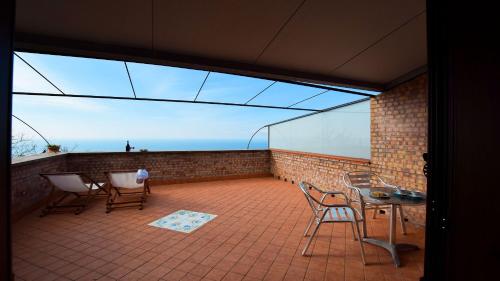 a balcony with chairs and a table and a window at Agriturismo Le Agavi in San Mauro Cilento
