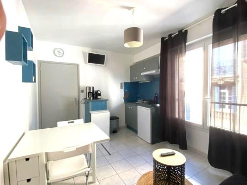 une cuisine avec des armoires bleues et une table blanche dans l'établissement Studio cœur de ville à deux pas de la grande plage des Sables d'Olonne, à Les Sables-dʼOlonne