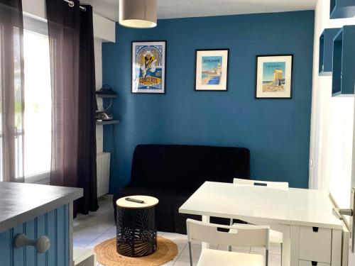 - un salon avec des murs bleus, une table et des chaises dans l'établissement Studio cœur de ville à deux pas de la grande plage des Sables d'Olonne, à Les Sables-dʼOlonne