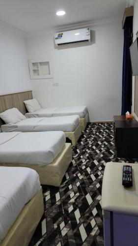 a room with a row of beds and a television at منازل المنال in Makkah