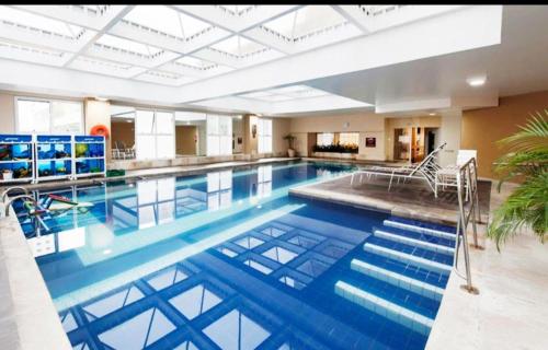 a large swimming pool in a large building at FLAT EM ALPHAVILLE HOTEL MELHOR LOCALIZAÇÃo in Barueri