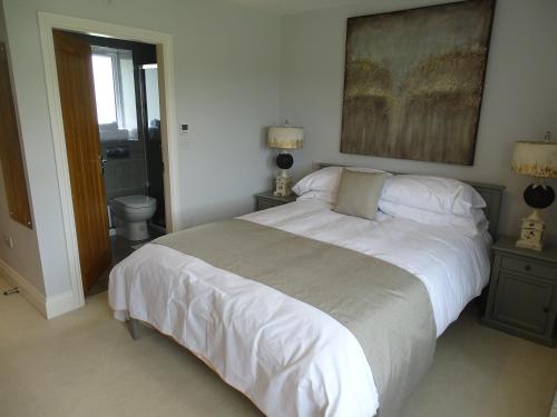 a bedroom with a large white bed and a bathroom at The Lodge - Bidford Grange Golf Course in Bidford