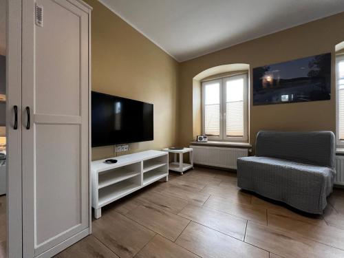 a living room with a flat screen tv and a chair at Apartament MRĄGOWIA in Mrągowo