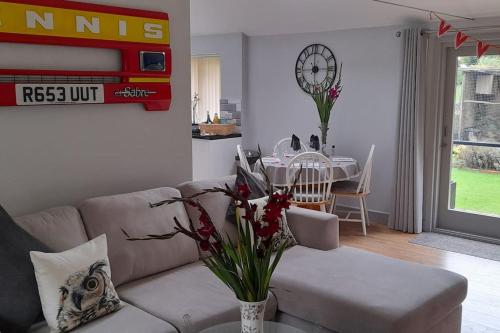 a living room with a couch and a table with a clock at Owlhoot Annexe in Sudbury